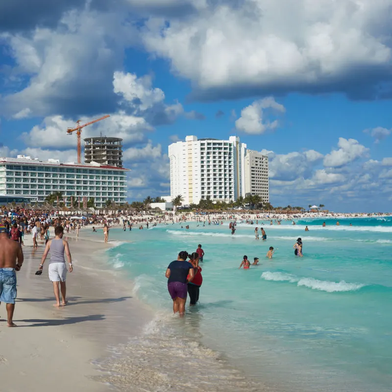 Travelers enjoying a stroll on Cancun's white sand beach