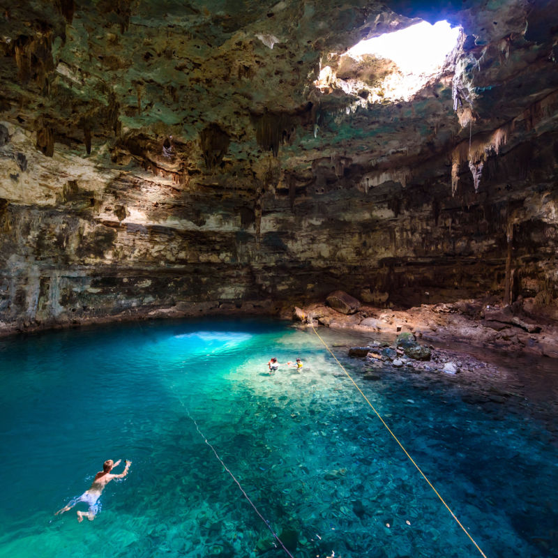A swimmer inside a large cenote 