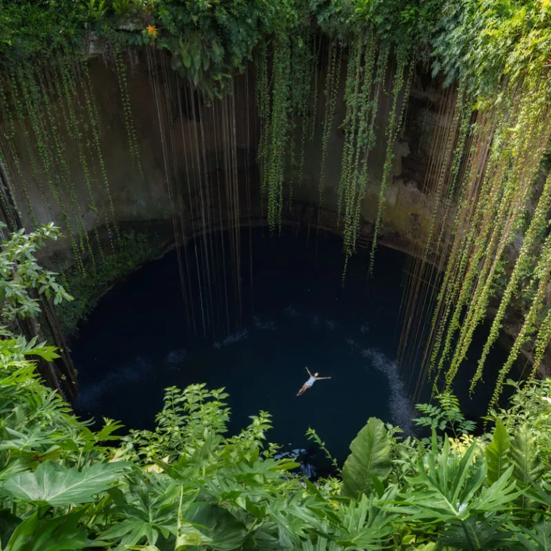 A large denote hole with a swimmer in the Mexican Caribbean