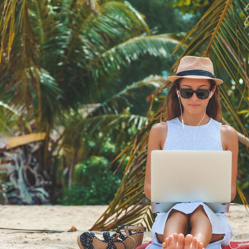 A digital nomad working on her laptop on the beach