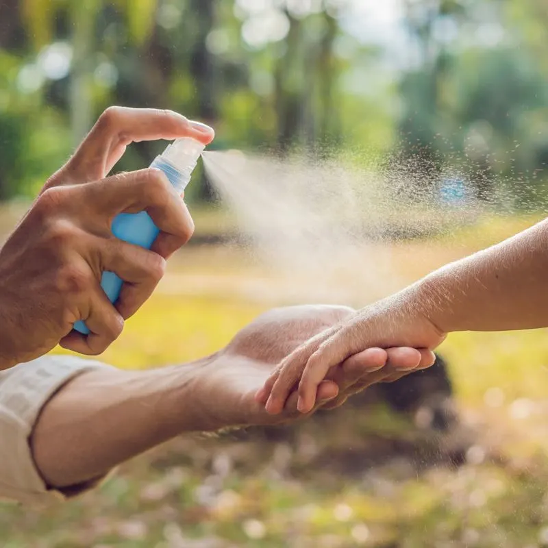 guy spraying his arm with bug spray