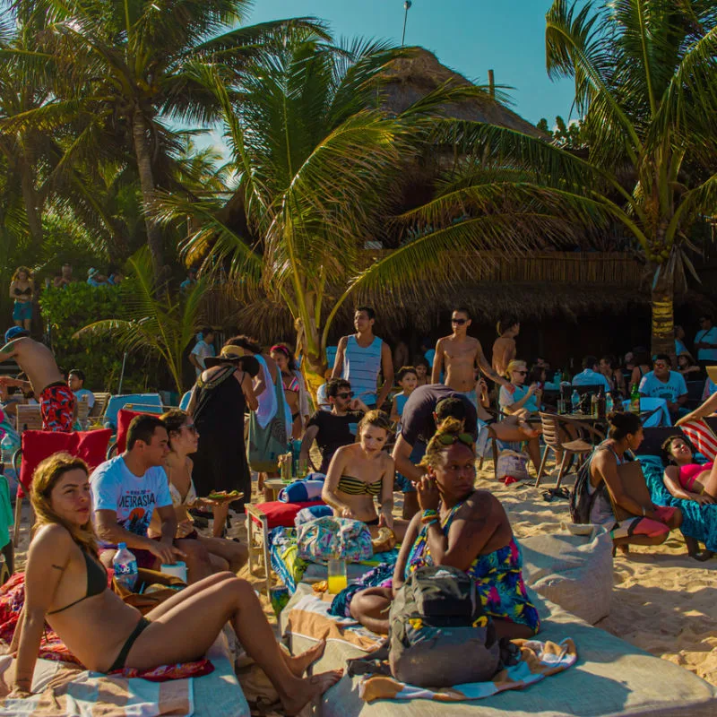 Beachgoers in Tulum on a white sand beach with palm trees