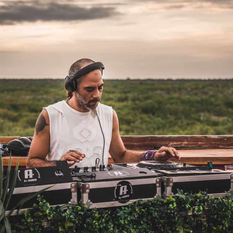 A DJ performing in a festival in Tulum surrounded by forest