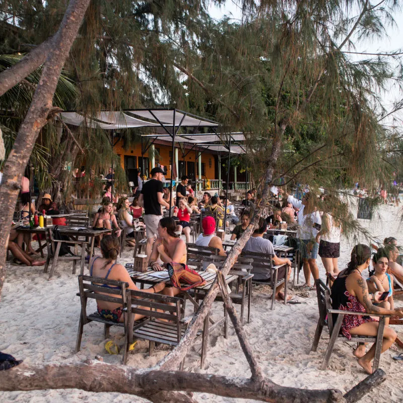 people sat outside on the beach enjoying drinks