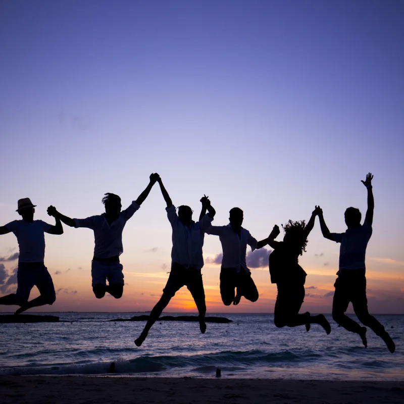 silhouette of friends jumping on the beach