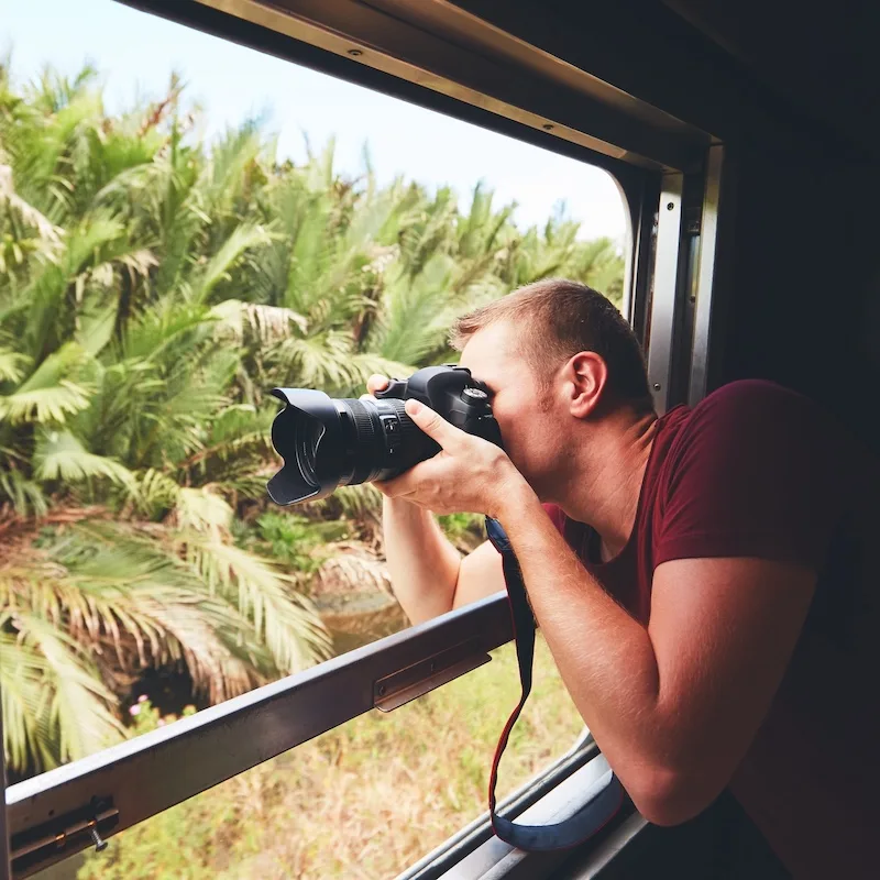 a train passenger taking photos out of the window with a professional camera