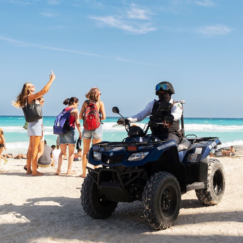 Tourists on a beach in Cancun with the police nearby.