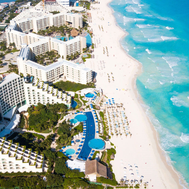 Aerial shot of a white sand beach in Cancun with resorts 