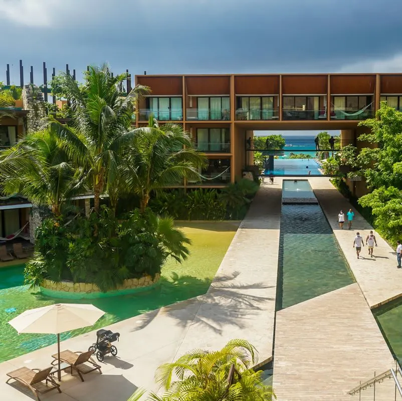 Hotel Xcaret grounds with water features and modern concrete walkways leading to the pool