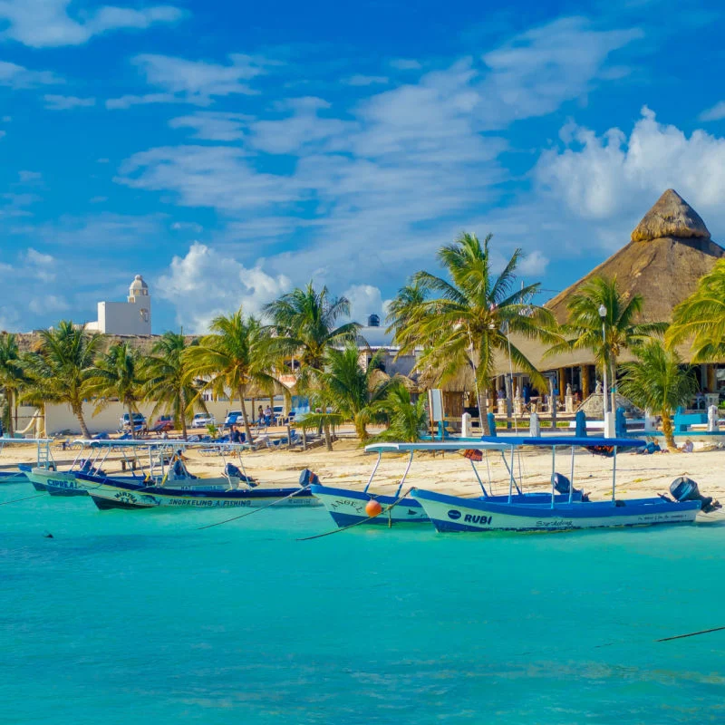 Crystal Clear water in Puerto Morelos beach with boats ready for traveler adventures 