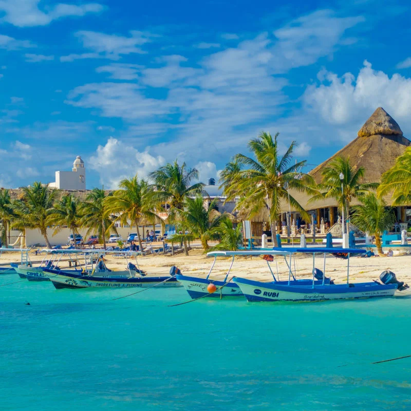 Crystal Clear water in Puerto Morelos beach with boats ready for traveler adventures