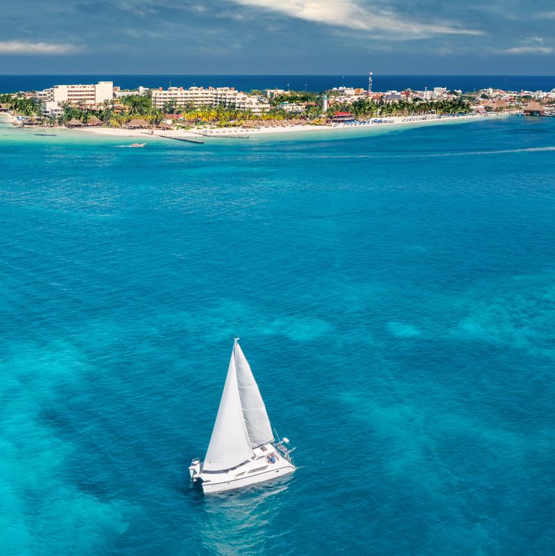 A small sailboat near isla mujeres with blue water 