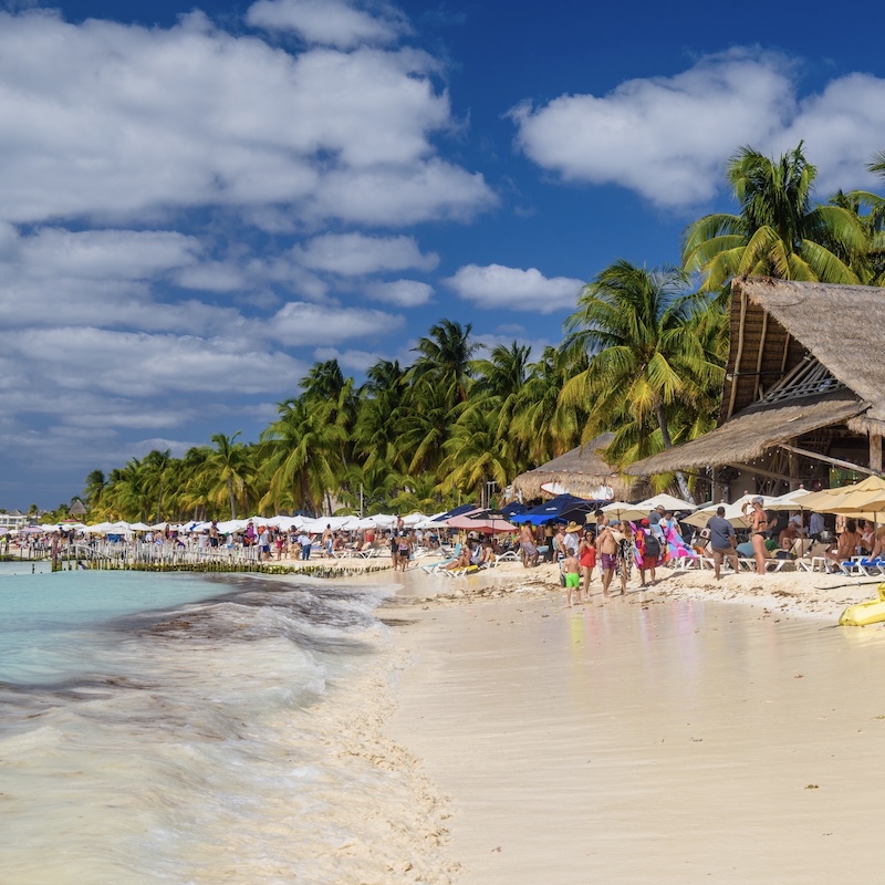 a white sand beach in Isla mujeres with travelers