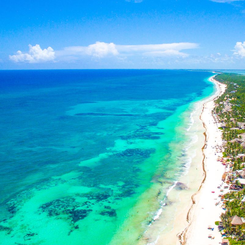 A stretch of white-sand beach in Tulum with blue waters