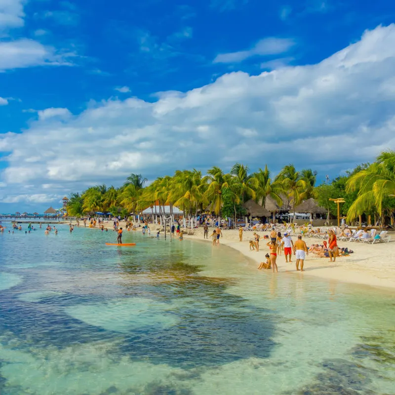 A beautiful white sand beach in Cancun with blue water and swimmers