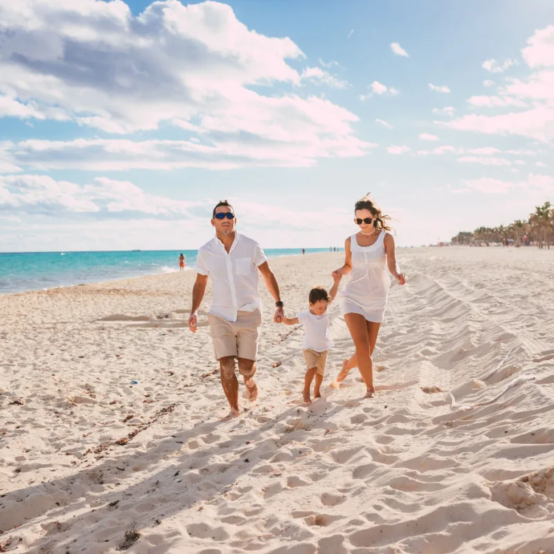 A family walking on a white sand beach in Cancun