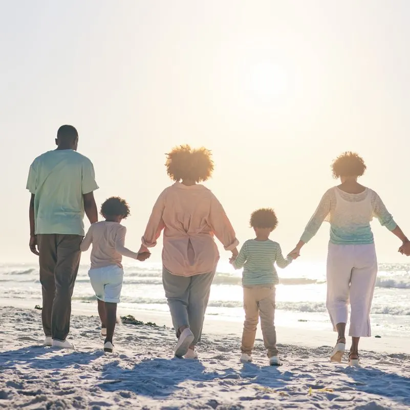 family hold hands on beach