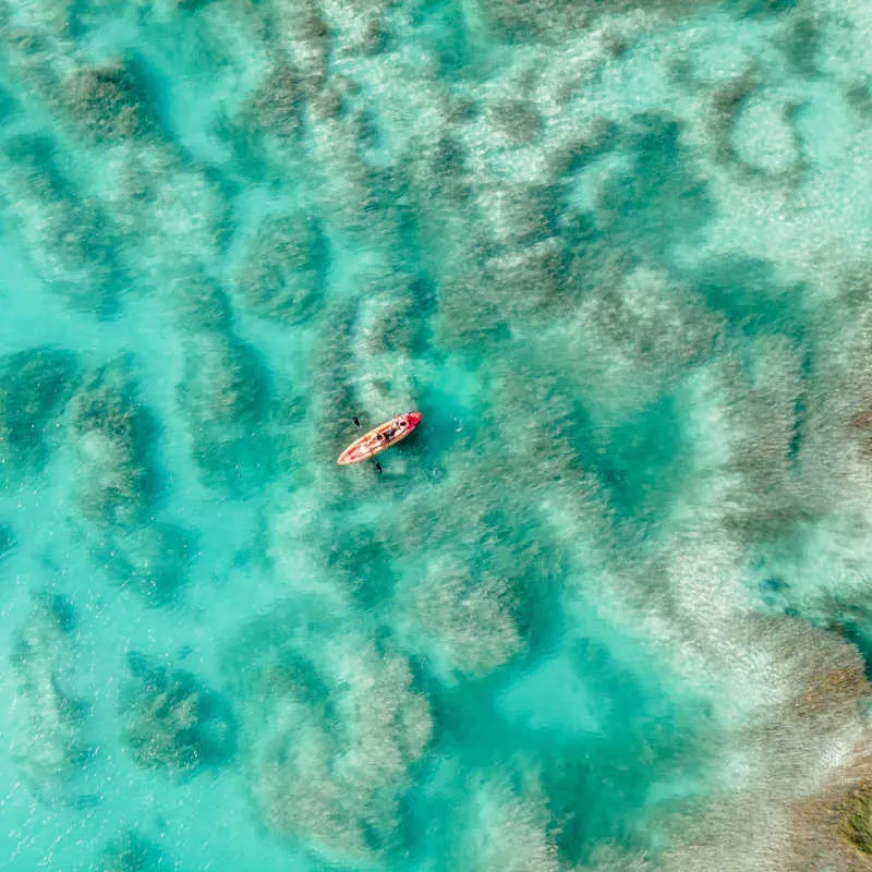 Aerial view of a boat on a colourful lagoon in Bacalar