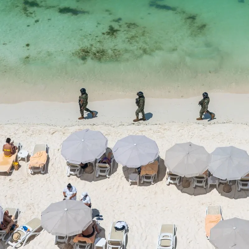 armed guards walking on a Cancun beach to protect travelers