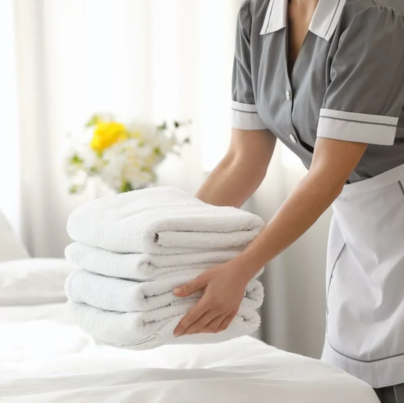A housekeeper leaving fresh towels in a room