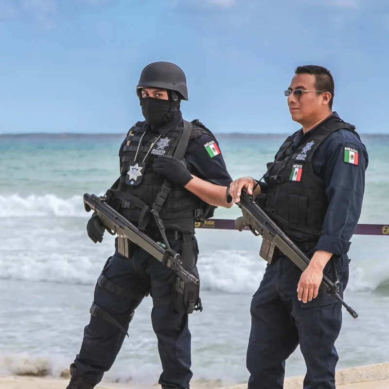 Armed police officers on a busy beach in Cancun