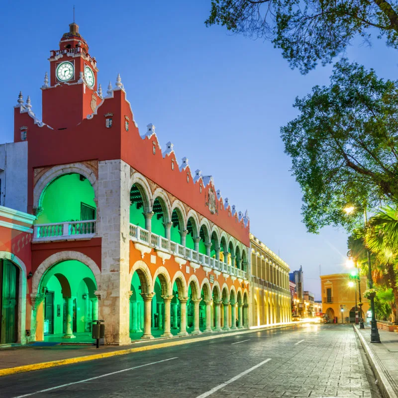 A colonial building lit up in green in the city of Merida