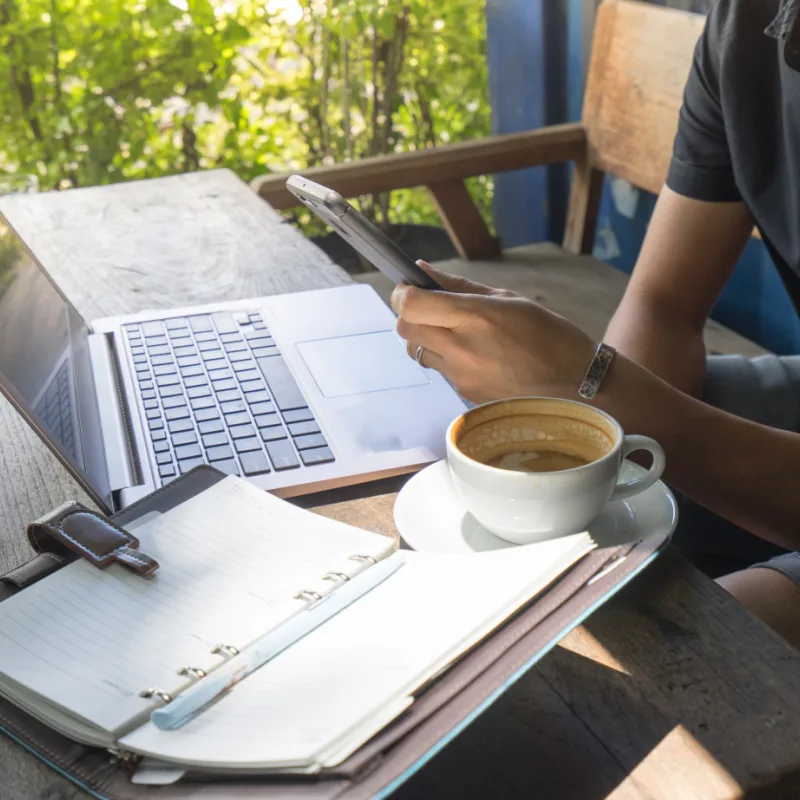 Person Looking at a Laptop and Having Coffee