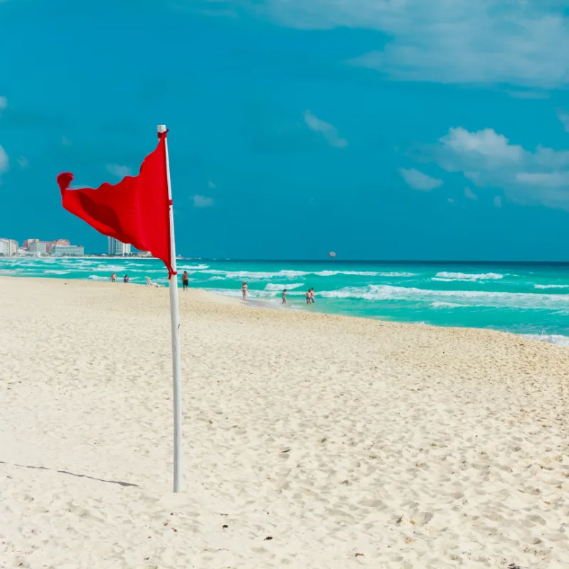 Red Flag on a Beach in Cancun with Tourists in the Background