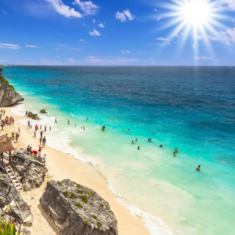 Travelers swimming in the sea below the tulum ruins