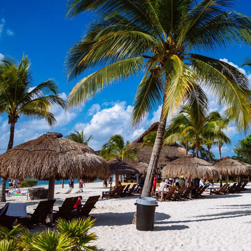 Mahahual beach area with sun loungers and palm sun shades
