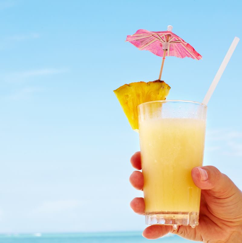 A cocktail with a mini umbrella in it on a sunny beach