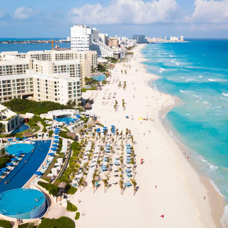 a large white sand beach in cancun with blue water