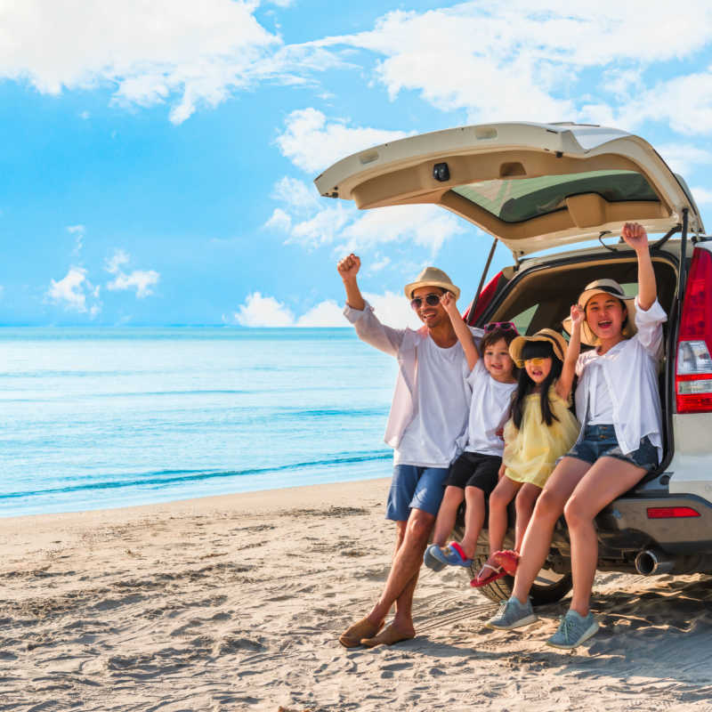 a family sitting on a rental car by the beach 