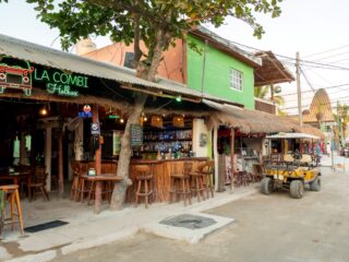 A shot of a bar restaurant and a golf cart taxi on a sandy street, Holbox, Mexico