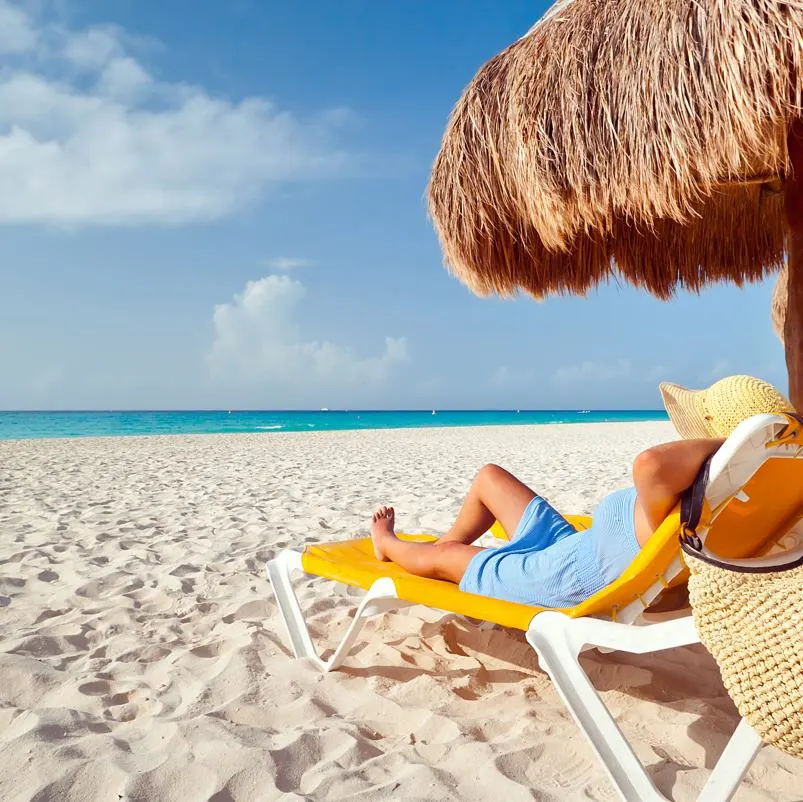 A lady relaxing on the beach on a deck chair