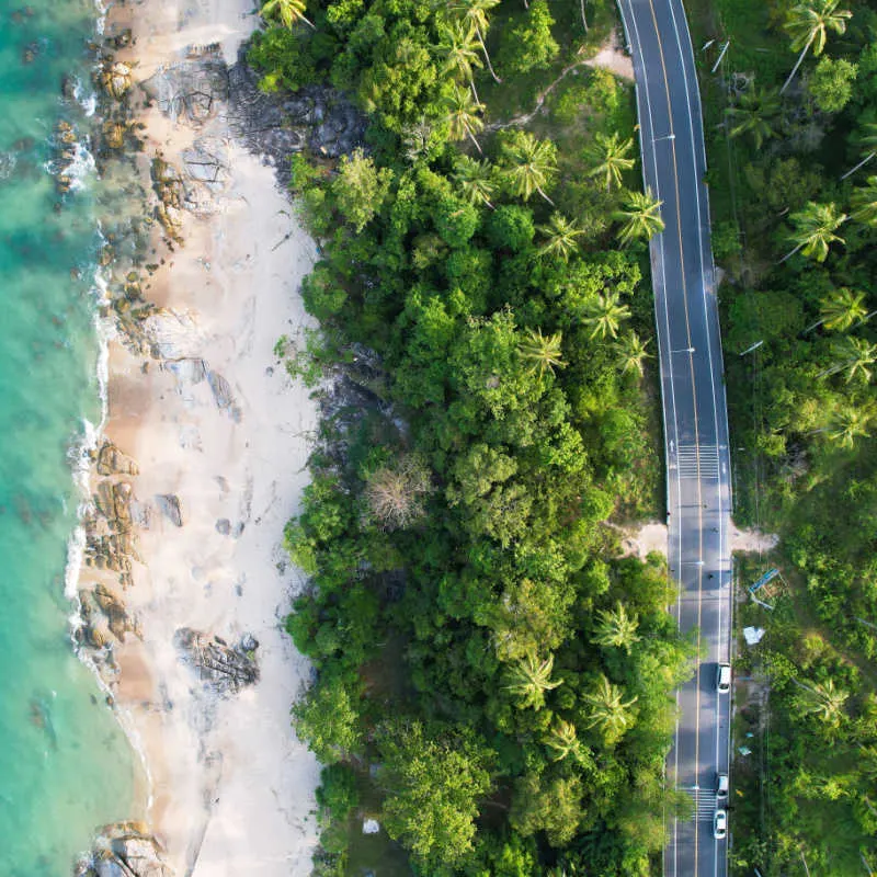 view of a road next to a white sand beach in cancun