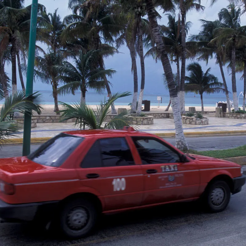 Old Cancun Taxi in Disrepair Driving Down the Street