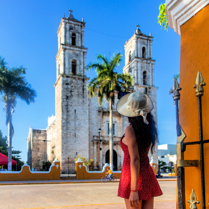 Tourist taking a photo with his mobile phone of the cathedral of San Servacio during the day in the city of Valladolid in Yucatan, Mexico. Clear blue sky
