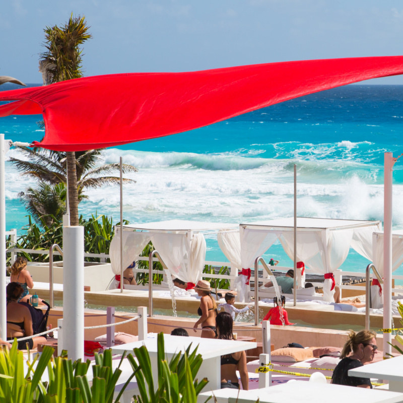 View of a hotel in cancun as people gather near the tables next to the beach