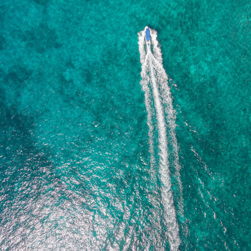 aerial view of boat traveling over turqouise water in the mexican caribbean