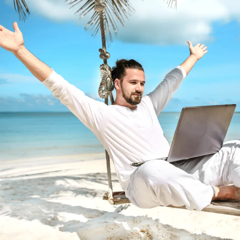 digital nomad on the beach on his laptop
