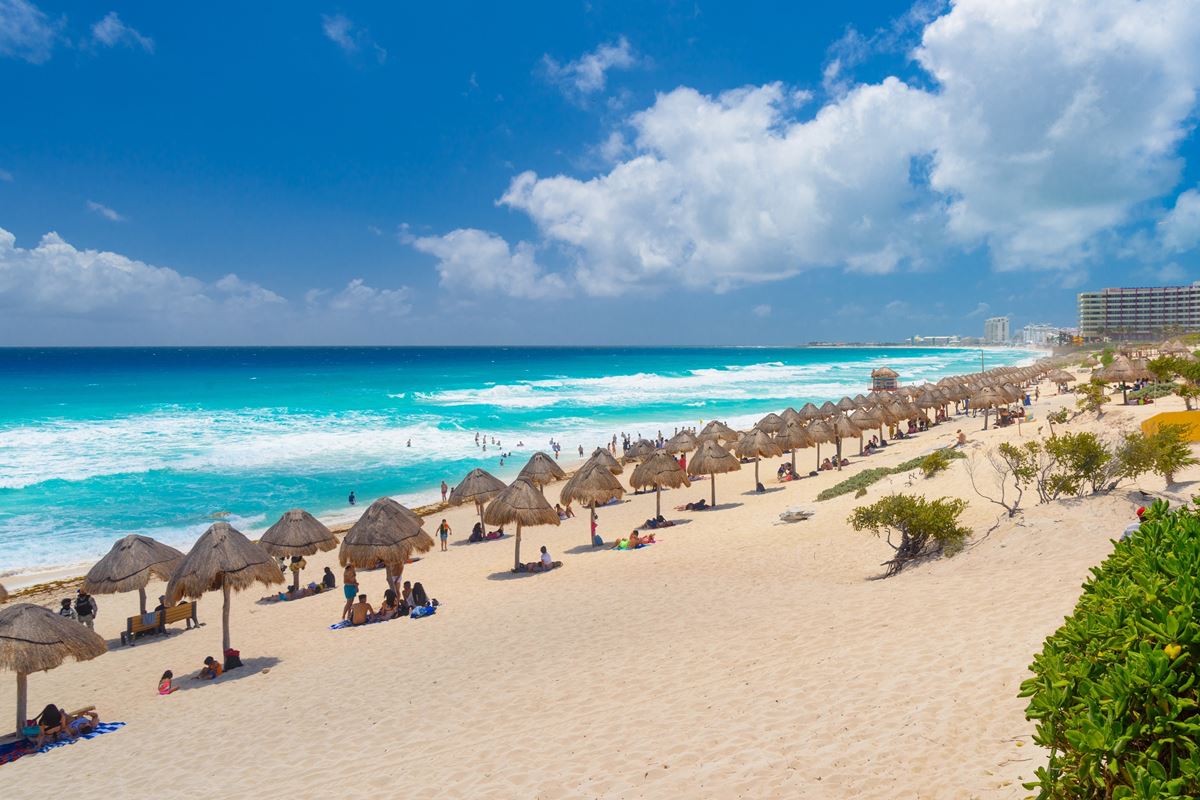 Cancun Beach with palapas and tourists on a sunny day