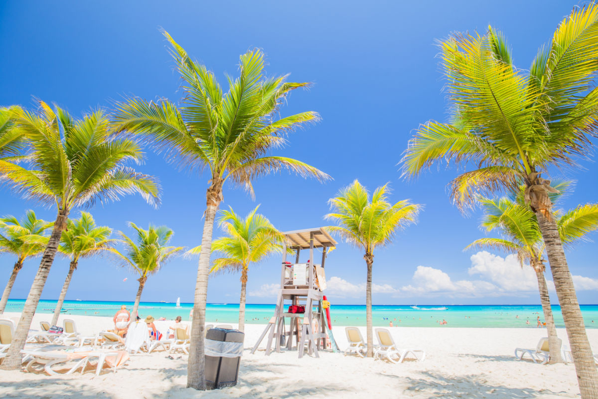 Cancun, Mexico, Nice beach with beach chairs, thatched umbrellas and palm trees. luxury beach against the background of the beauty of the sea with coral reefs. summer holiday.