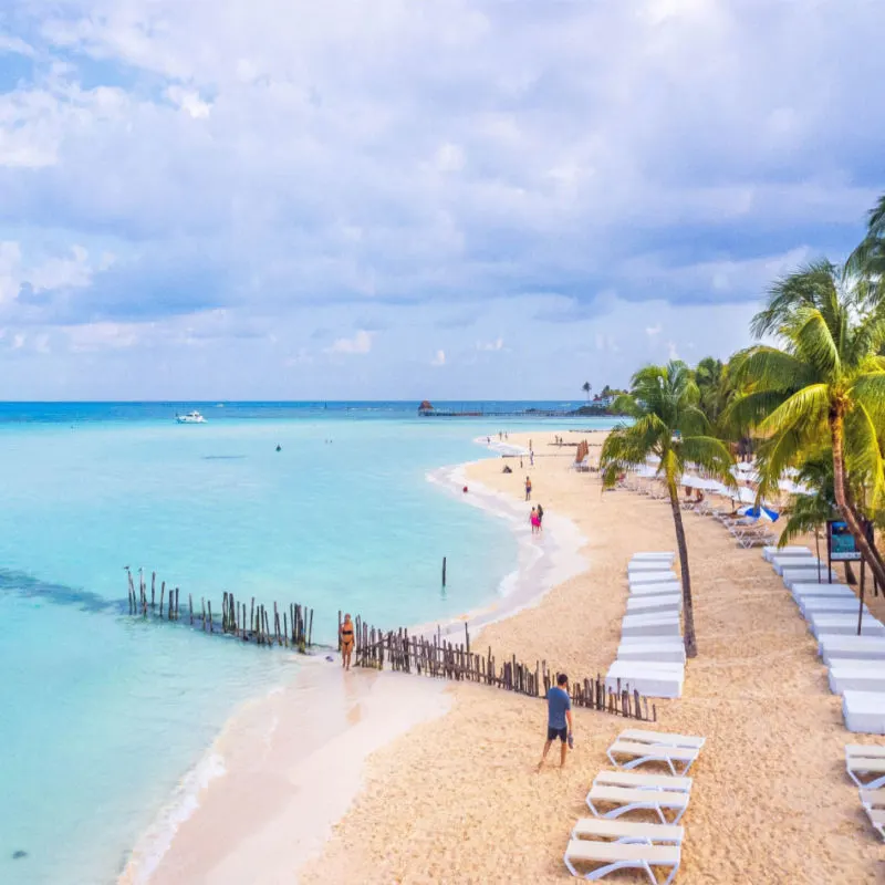 a long white sand beach in costa mujeres with palm trees