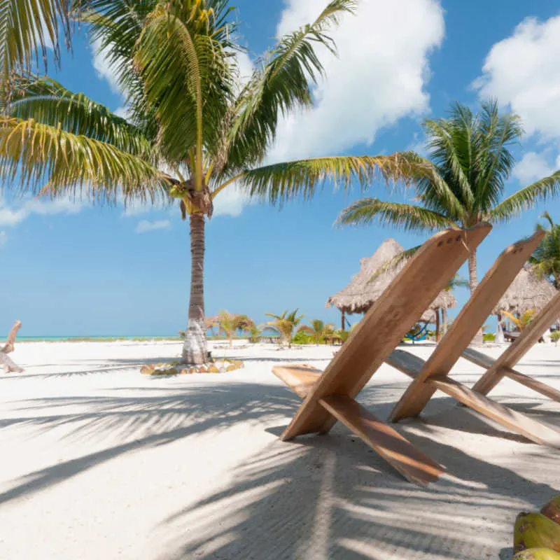 a white sand beach and chairs in holbox