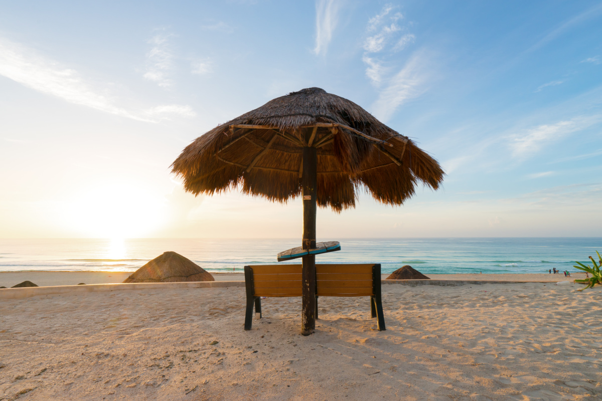 sunrise on an empty Playa Delfines beach in Cancun, with beach umbrella center