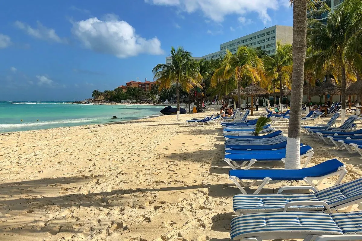 Mexican Caribbean beach with palm trees, resorts, and sun loungers