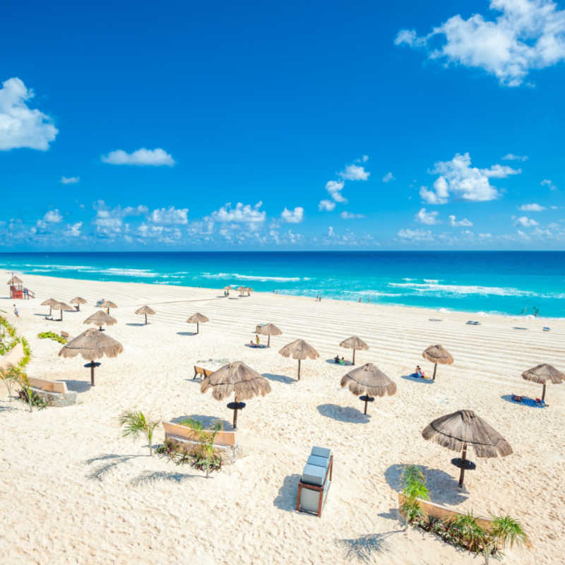 a large white sand beach in cancun with the sea