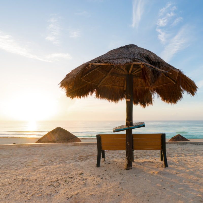 sunrise on an empty Playa Delfines beach in cancun, with beach umbrella center