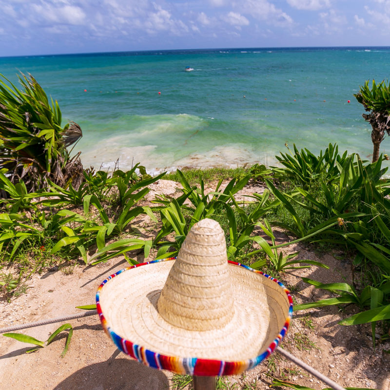 view of the beach below Tulum ruins with Mexican sombreo hat in the middle